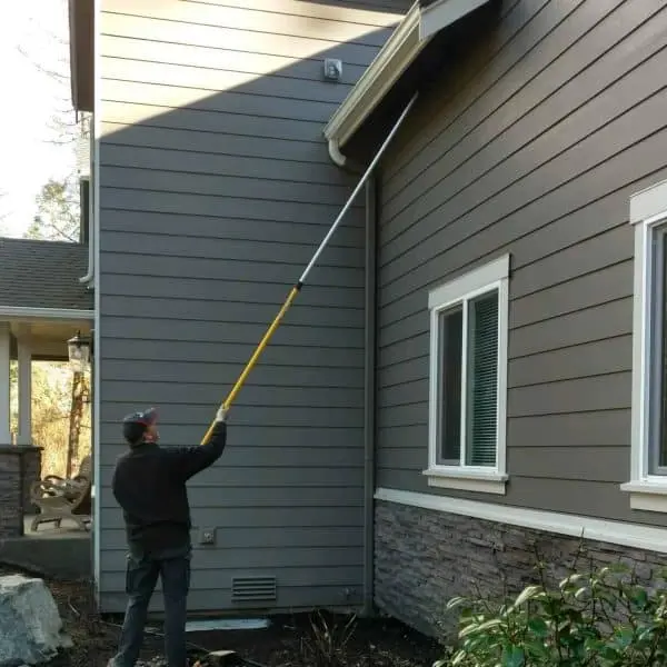 Pest control technician treating the exterior of a house